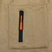 Close-up of a beige fabric pocket with an orange zipper pull.