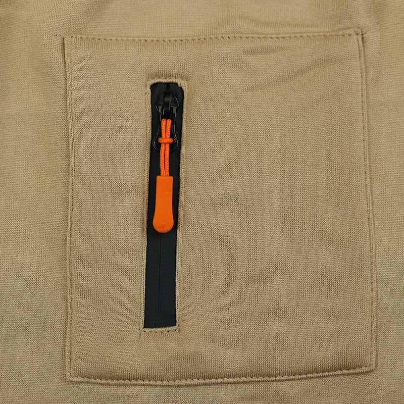 Close-up of a beige fabric pocket with an orange zipper pull.