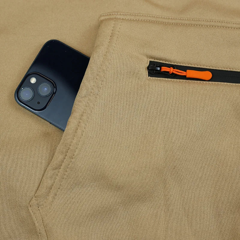 Phone in a pocket of beige pants with an orange zipper pull.