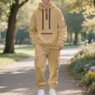 Person wearing a beige hoodie and cargo pants standing on a path in a park.