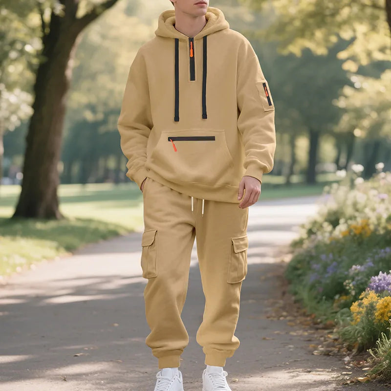 Person wearing a beige hoodie and cargo pants standing on a path in a park.