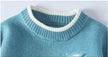 Close-up of a blue sweater with white trim on a light gray background
