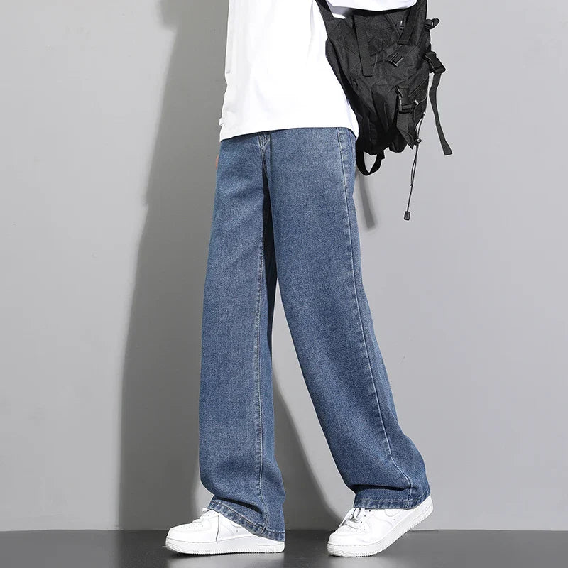 Person wearing blue jeans and white sneakers with a black backpack on a gray background