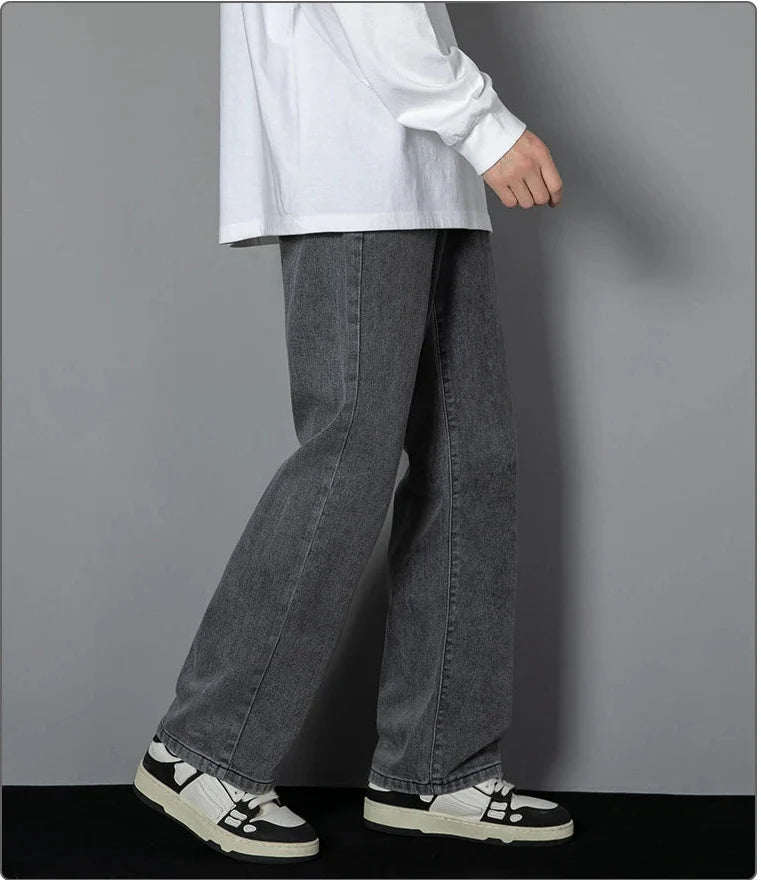 Person wearing gray wide-leg jeans and white sneakers on a plain background