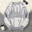 Gray sweater with white abstract patterns on a textured surface