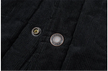 Close-up of black corduroy fabric with two buttons on a white background
