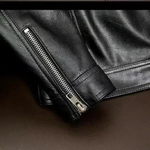 Close-up of a black leather jacket with zipper detail on a dark background