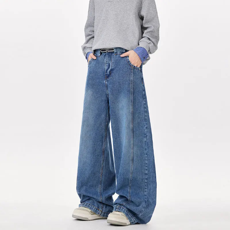 Person wearing wide-leg blue jeans and a gray sweater on a white background