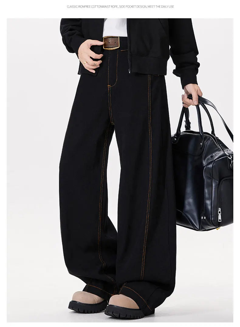 Person wearing black wide-leg pants holding a black bag on a white background