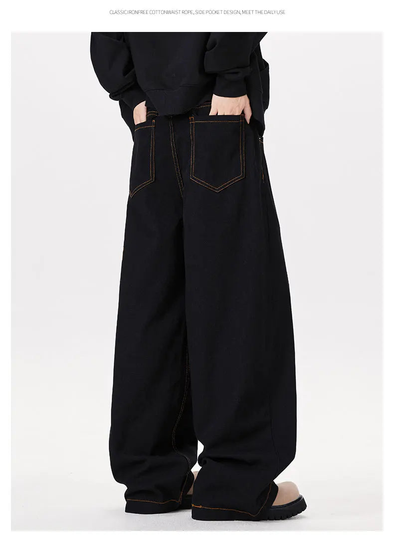 Person wearing black wide-leg jeans on a white background