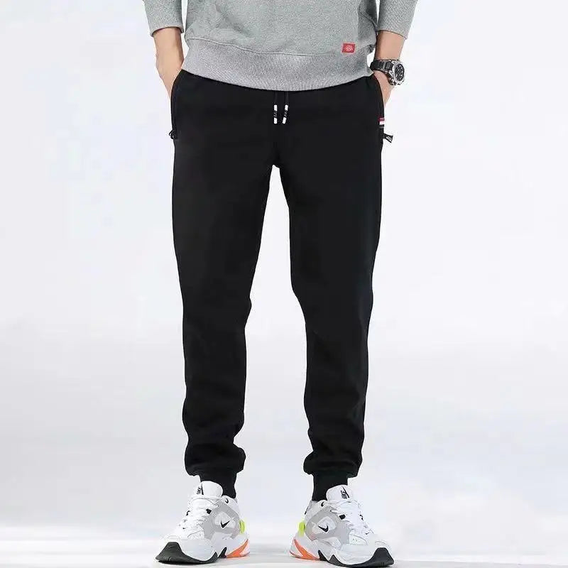 Person wearing black pants and white sneakers on a white background