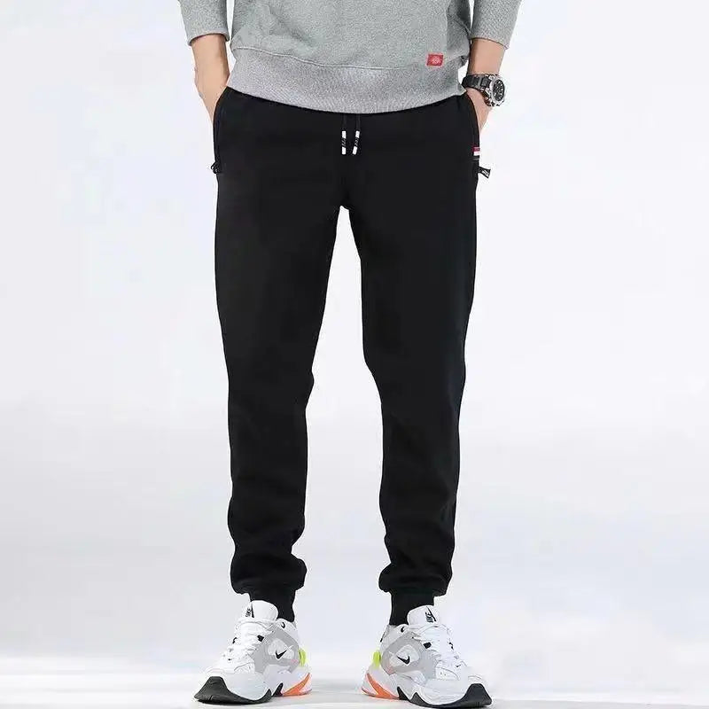 Person wearing black pants and white sneakers on a white background