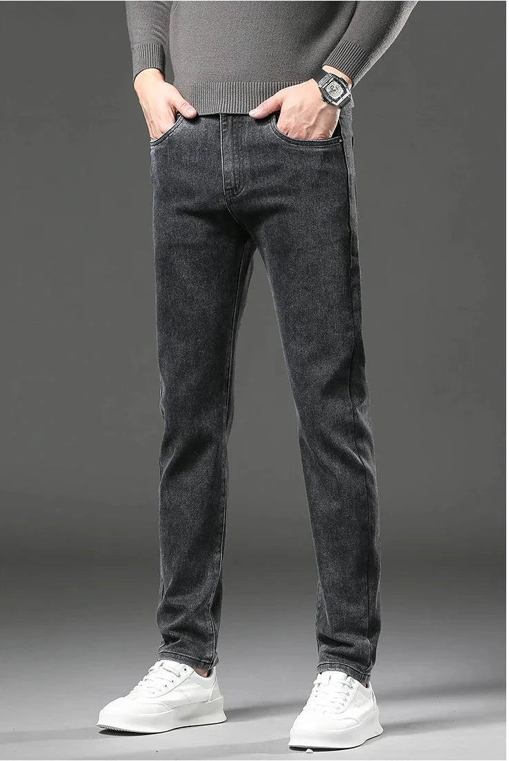 Person wearing dark gray jeans and a gray sweater on a gray background