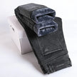 Folded gray jeans with a white box on a light gray background