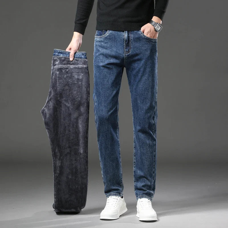 Person holding a pair of dark gray jeans next to a pair of blue jeans on a gray background