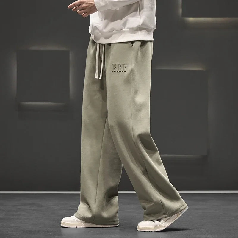 Person wearing olive green pants with a brand logo on a dark background