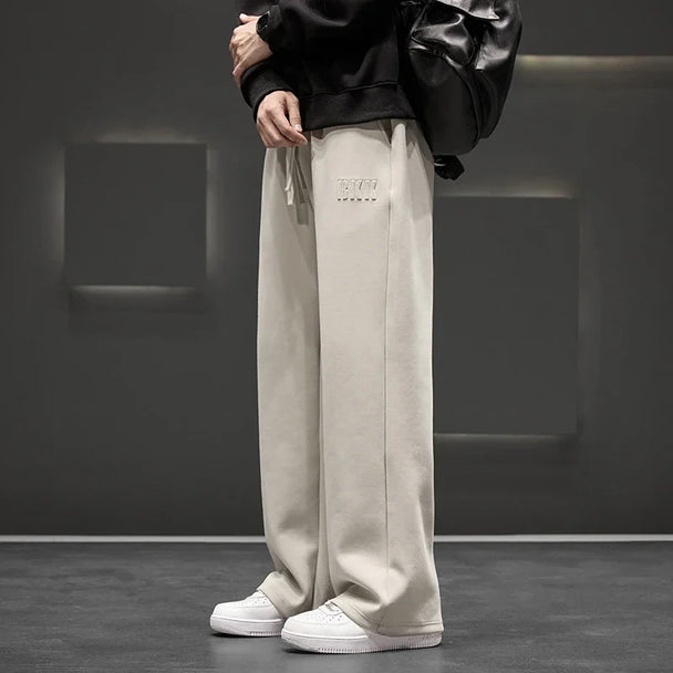 Person wearing beige pants with a brand logo in a minimalistic setting