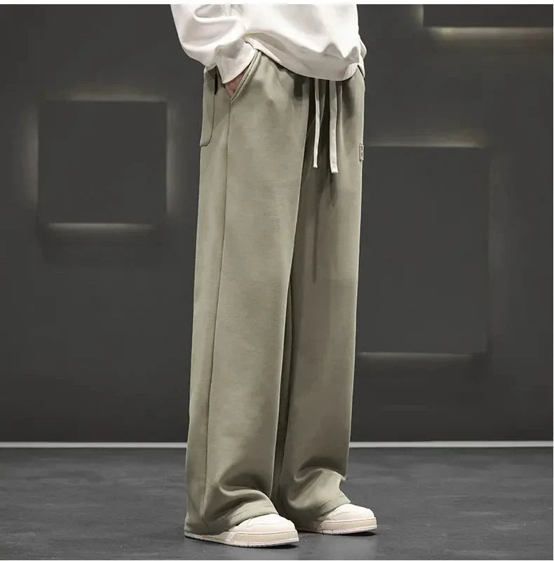 Person wearing beige wide-leg pants and white shoes on a dark background