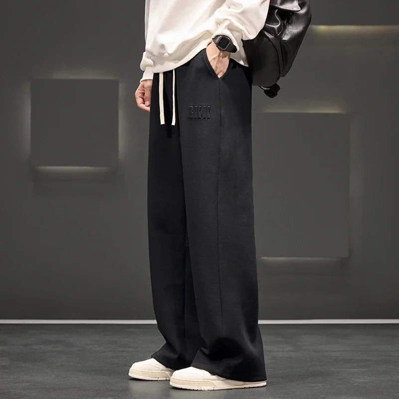 Person wearing black pants with a brand logo in a minimalistic setting