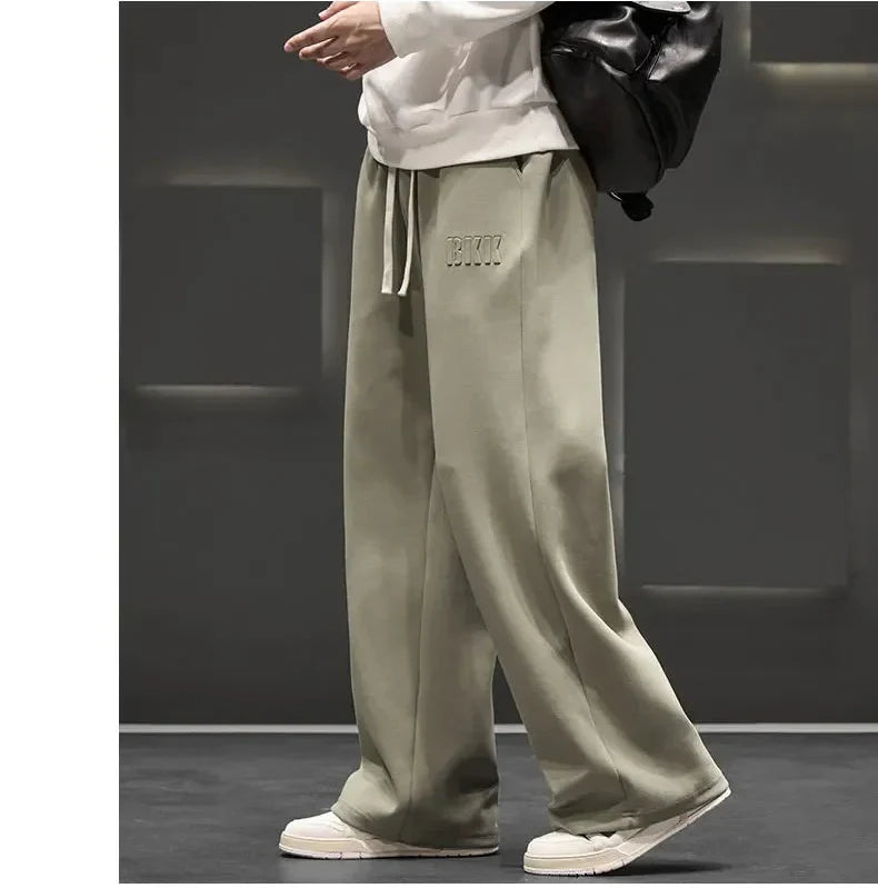 Person wearing beige pants with a logo on a dark background