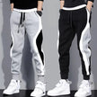 Two pairs of jogger pants, one gray and one black, with white side stripes, worn by models against a gray background.