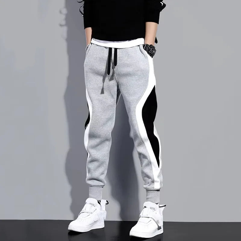 Gray sweatpants with white and black stripes worn by a person on a gray background