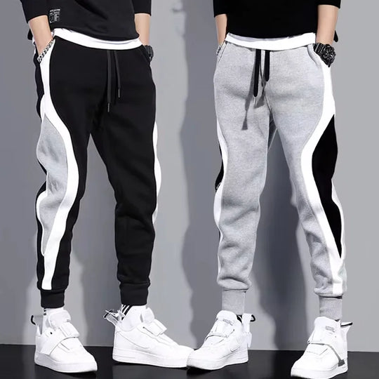 Black and gray jogger pants with white stripes worn by two people on a gray background