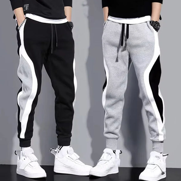 Black and gray jogger pants with white stripes worn by two people on a gray background