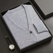 Gray cardigan in a black box with a watch on a dark surface