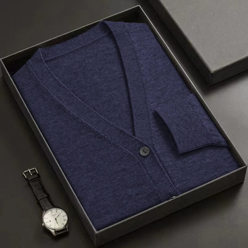 Blue cardigan in a black box with a watch on a dark surface