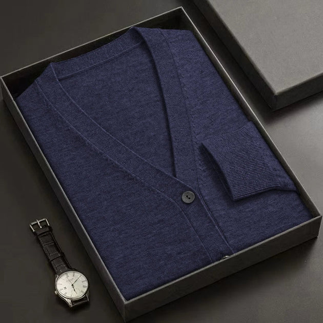 Blue cardigan in a black box with a watch on a dark surface