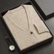 Beige cardigan in a black box with a watch on a dark surface