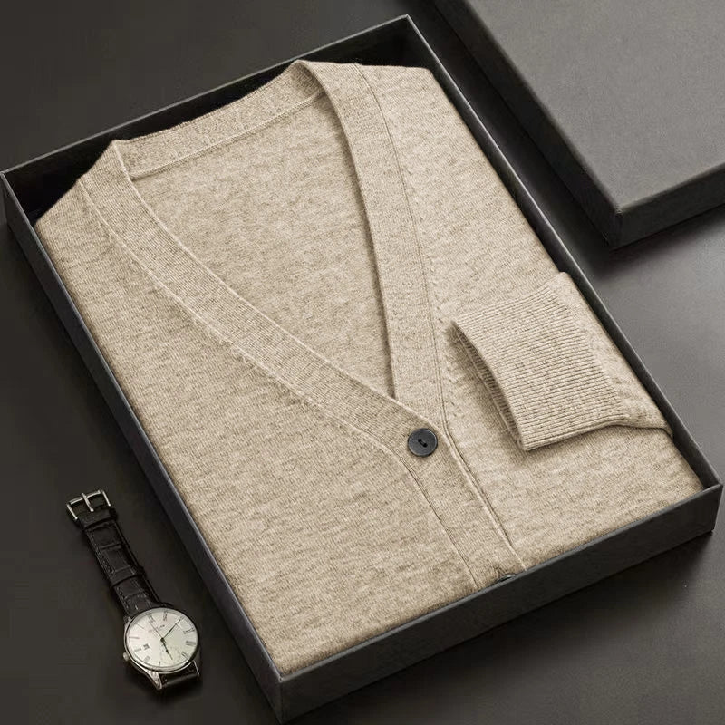 Beige cardigan in a black box with a watch on a dark surface