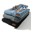 Stack of folded jeans with visible brand labels on a white background