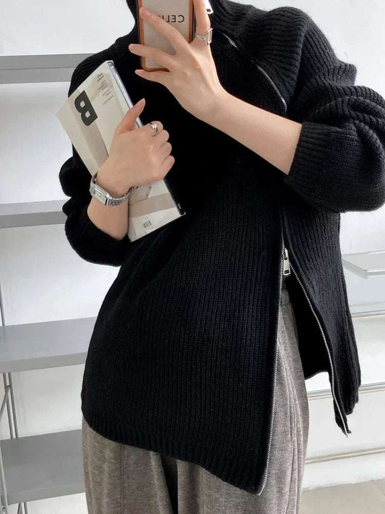 Person wearing a black sweater holding a phone in an indoor setting