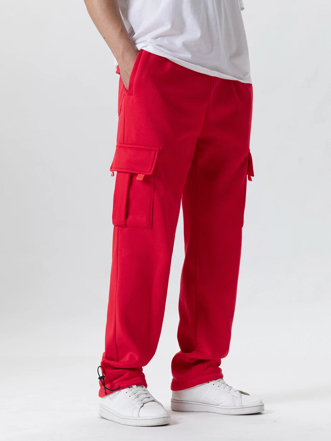 Person wearing red cargo pants and white sneakers on a light gray background