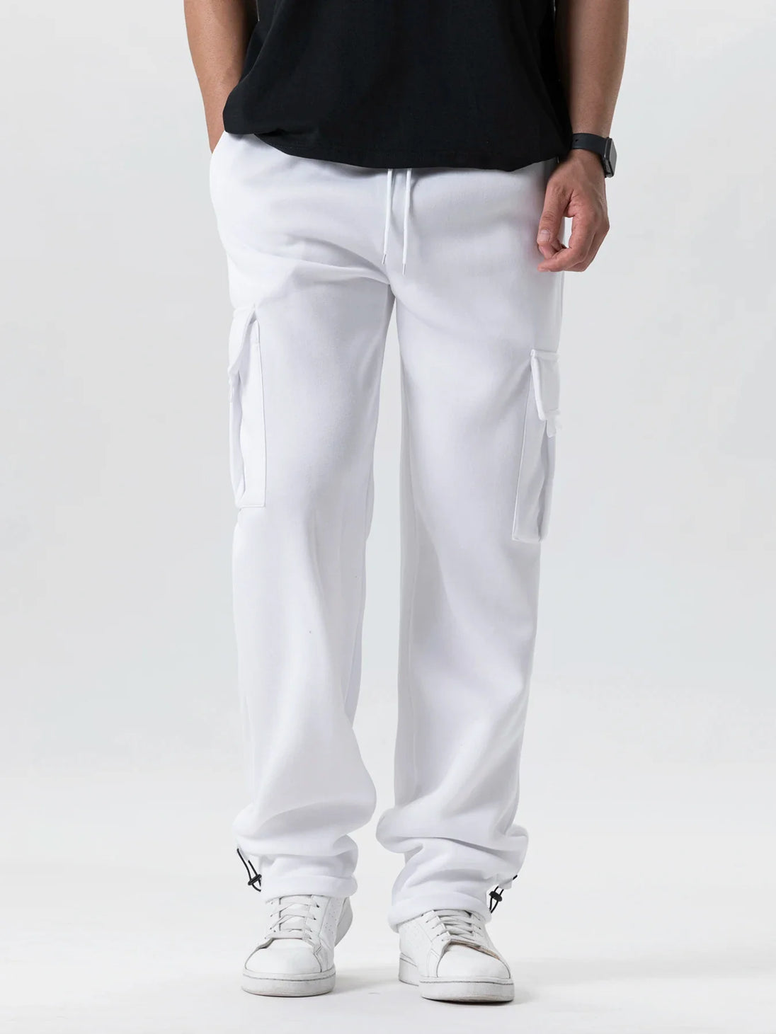 Person wearing white cargo pants and black shirt on a white background
