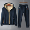 Navy blue hoodie and jogger pants set on hangers against a gray background