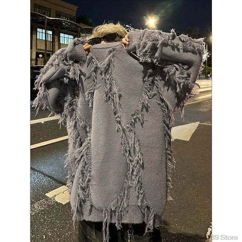 Person wearing a gray fringed coat on a street at night.
