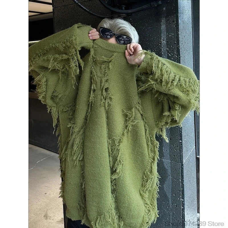 Person wearing a green fringed sweater with sunglasses on a neutral background