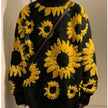 Black sweater with yellow sunflower patterns against a neutral background