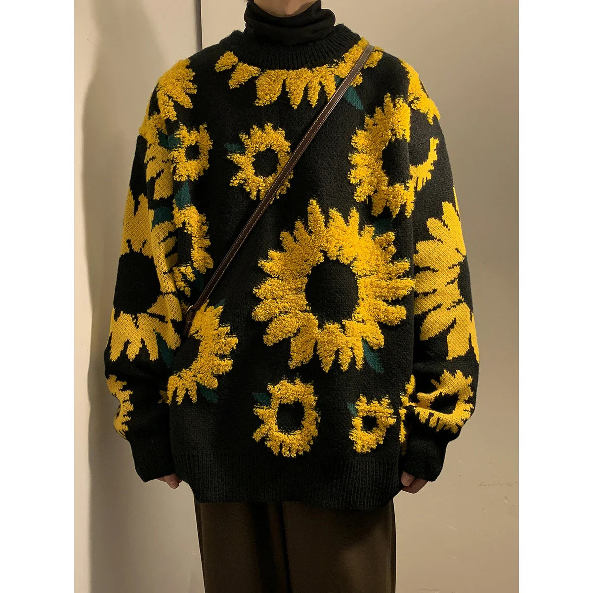 Person wearing a black sweater with yellow sunflower patterns against a neutral background