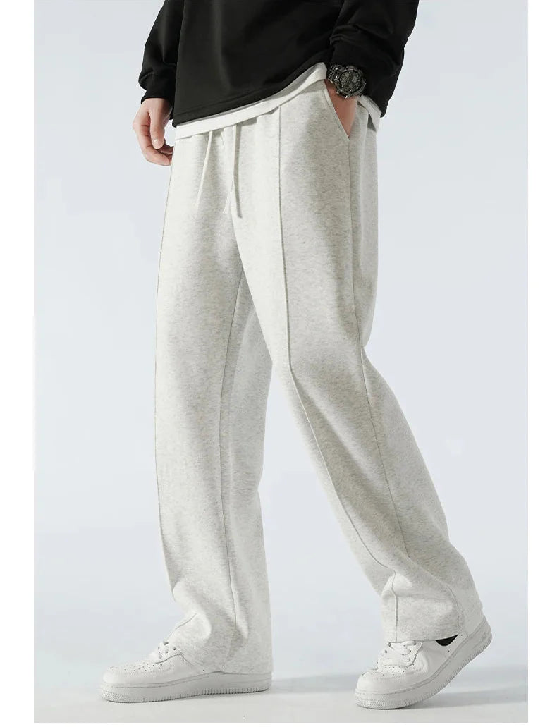 Person wearing light gray sweatpants with a plain background