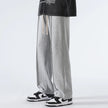 Person wearing gray sweatpants and black sneakers on a white background