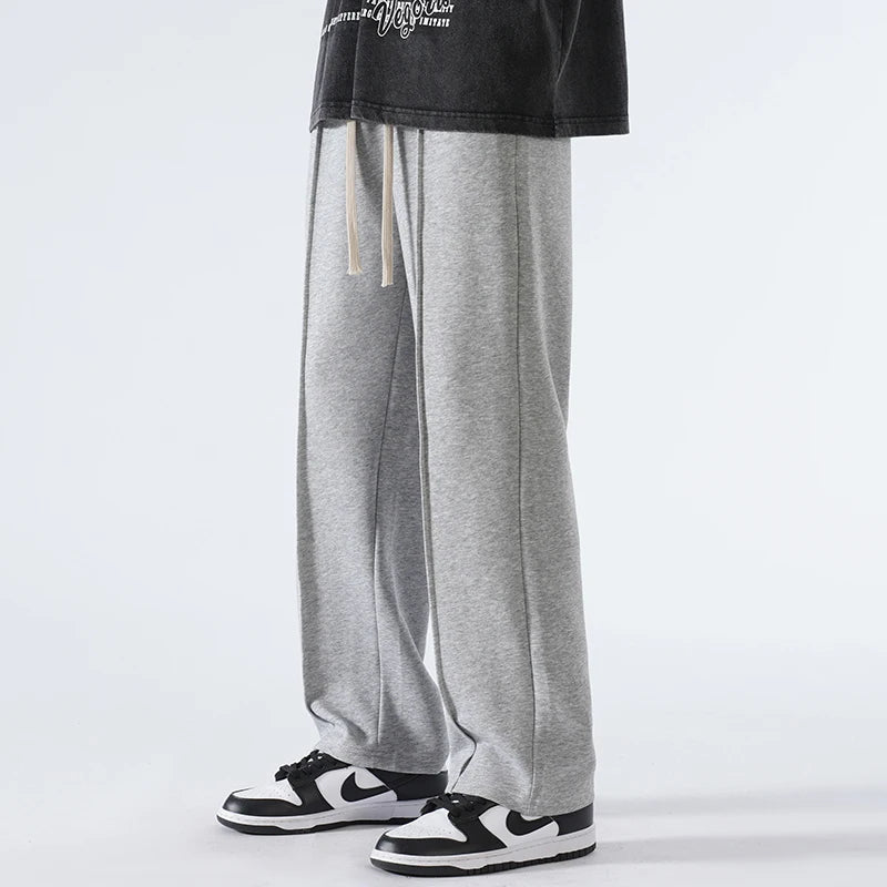 Person wearing gray sweatpants and black sneakers on a white background